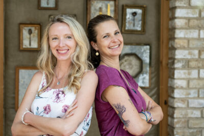 Schlanktastisch Community: Zwei Frauen, Rücken an Rücken, lächeln in die Kamera. Mitgliederbereich.